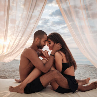 Passionate,Young,Couple,Sitting,In,Bed,On,The,Beach
